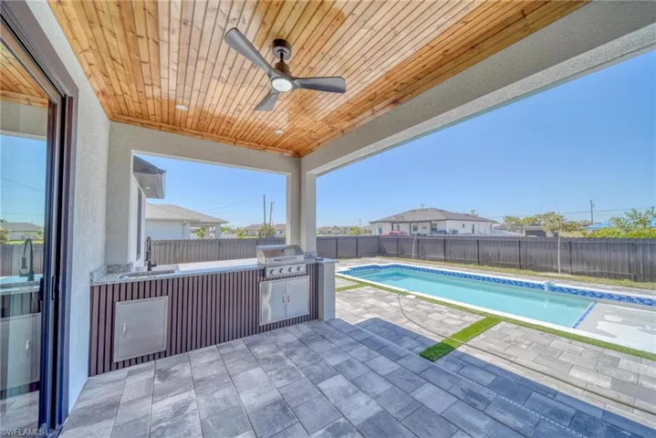 View of swimming pool featuring a fenced backyard, a sink, exterior kitchen, grilling area, and a patio area