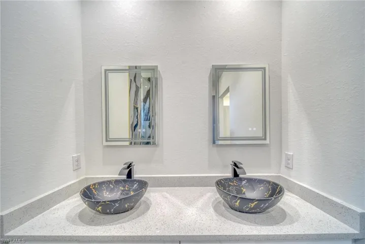 Interior details featuring double vanity, a sink, and a textured wall