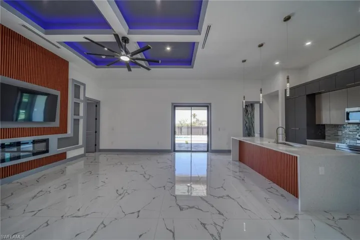 Kitchen featuring marble finish floor, light countertops, stainless steel microwave, open floor plan, and modern cabinets
