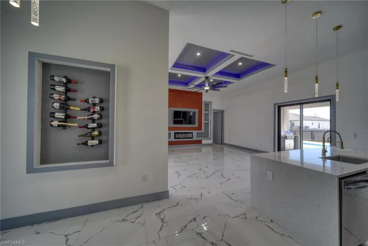 Kitchen with stainless steel dishwasher, baseboards, coffered ceiling, and a sink