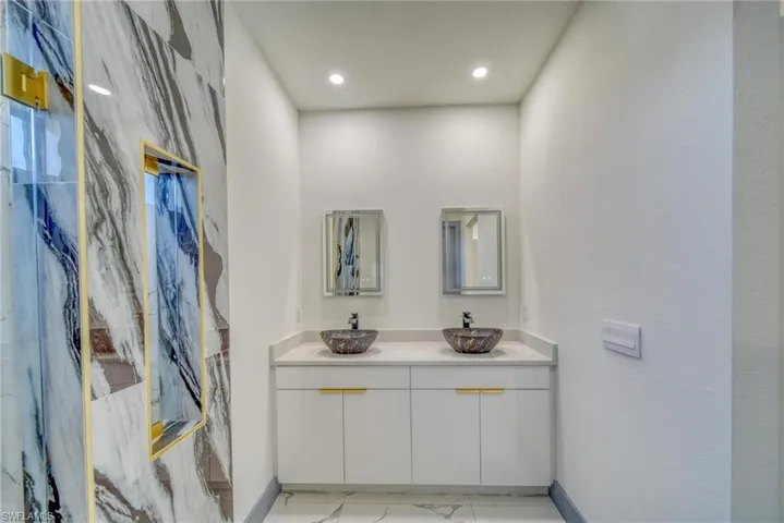 Bathroom with marble finish floor, a sink, baseboards, and double vanity