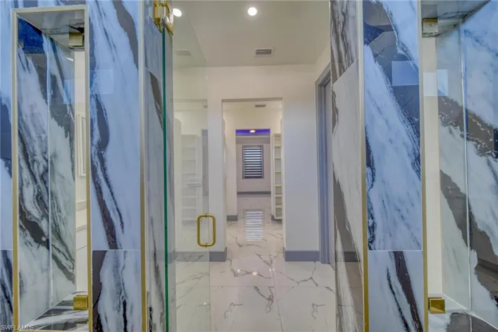 Bathroom with marble finish floor, a marble finish shower, and visible vents