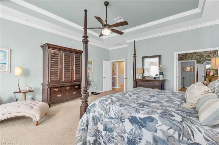 Bedroom featuring a raised ceiling, carpet floors, crown molding, and a ceiling fan