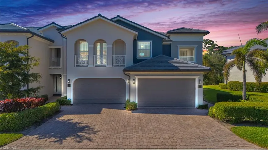 View of front of property featuring a balcony, stucco siding, decorative driveway, and a garage