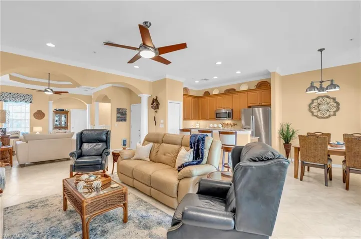 Living room with arched walkways, a ceiling fan, ornamental molding, light tile patterned flooring, and recessed lighting