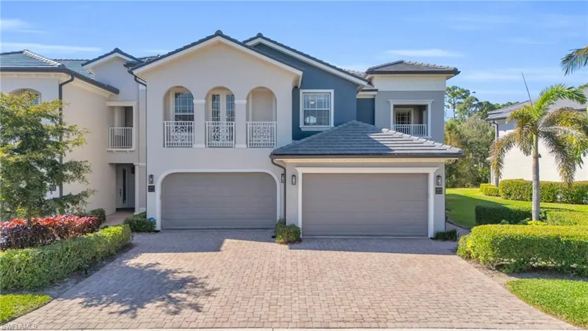 View of front facade featuring a balcony, stucco siding, decorative driveway, and an attached garage