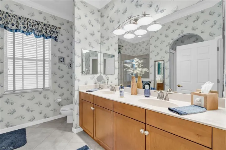 Bathroom with crown molding, light tile patterned floors, and double vanity