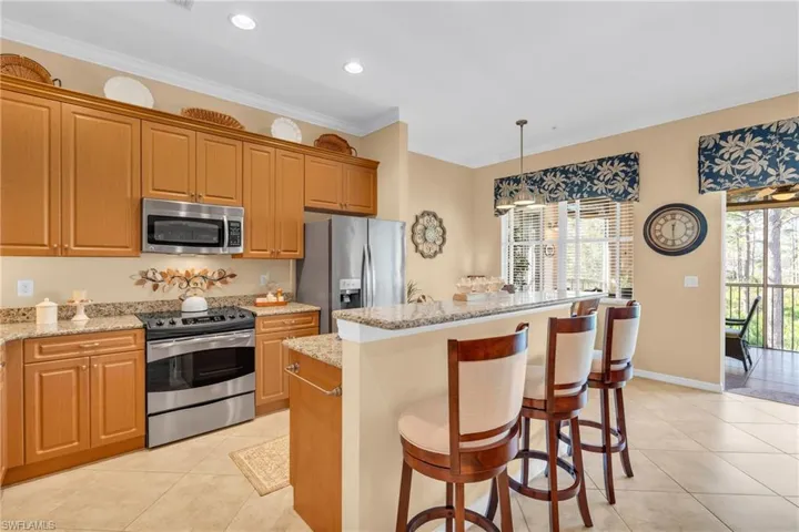 Kitchen with a breakfast bar area, appliances with stainless steel finishes, a center island, pendant lighting, and light stone counters