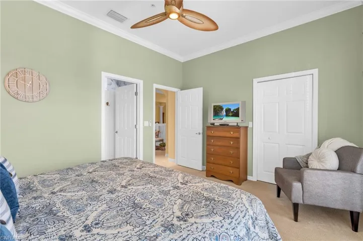 Bedroom with crown molding, light colored carpet, a closet, and a ceiling fan