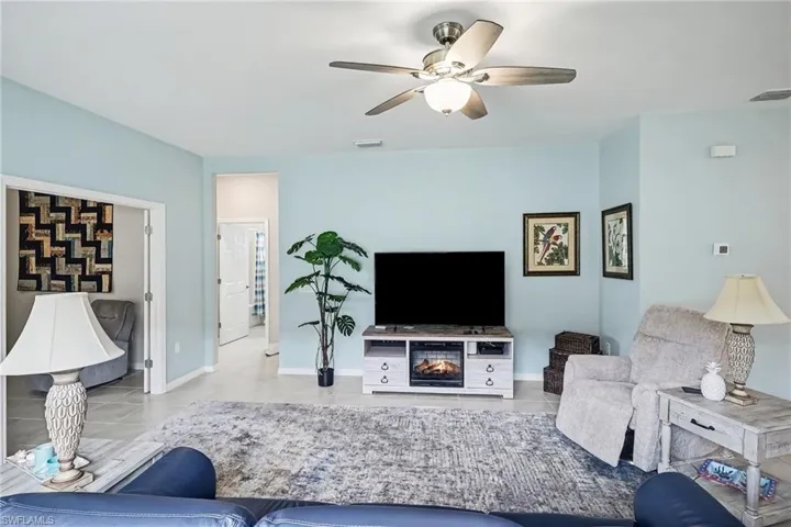 Recessed lighting, ceiling fan with integrated light, tile flooring, and a decorative fireplace