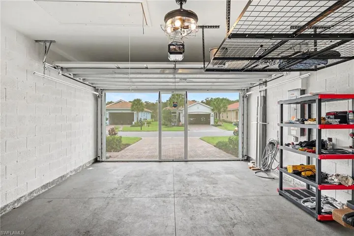 Spacious garage with concrete flooring, overhead storage racks, and a ceiling-mounted fan fixture
