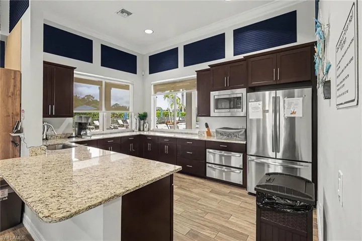 Kitchen featuring wood-finish flooring, dark wood cabinetry, light-toned countertops, and stainless steel appliances