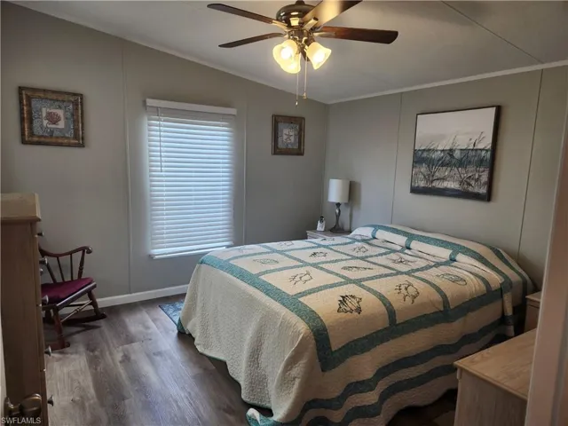 Bedroom with dark wood-type flooring, crown molding, and ceiling fan