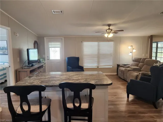 Living room featuring wood-type flooring, ornamental molding, and ceiling fan