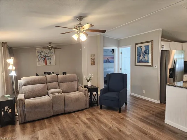 Living room featuring wood-type flooring, crown molding, and ceiling fan