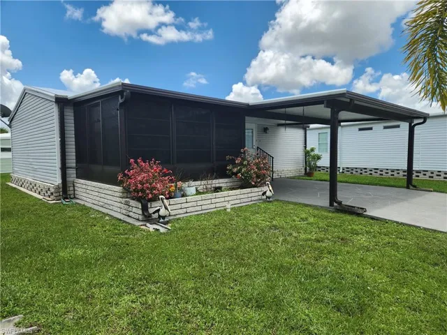 Back of house featuring a carport and a yard