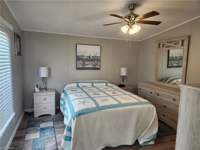 Bedroom with multiple windows, ceiling fan, dark hardwood / wood-style floors, and crown molding