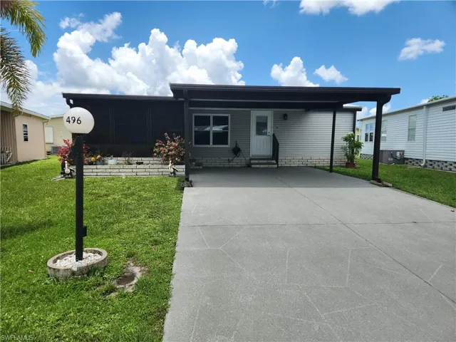 View of front of property featuring a carport and a front lawn