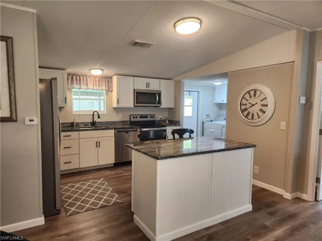 Kitchen with a center island, white cabinetry, dark hardwood / wood-style flooring, and stainless steel appliances