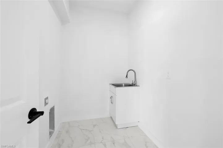 Laundry area featuring sink and light tile floors