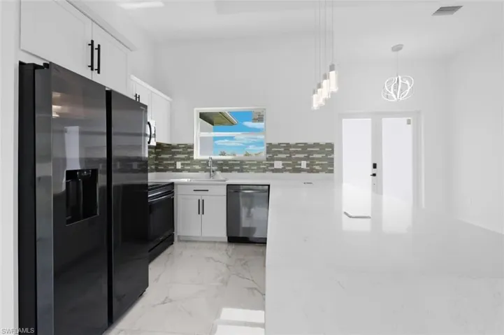 Kitchen featuring dishwasher, stove, black fridge, backsplash, and light tile floors