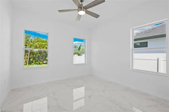 Tiled empty room with plenty of natural light and ceiling fan