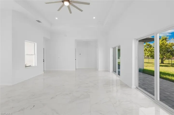 Spare room with a high ceiling, a wealth of natural light, ceiling fan, and light tile floors