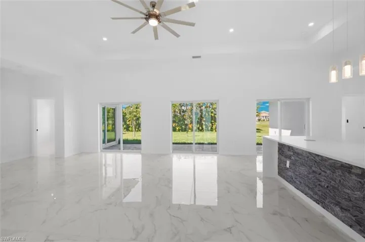 Unfurnished living room with a high ceiling, ceiling fan, and light tile floors