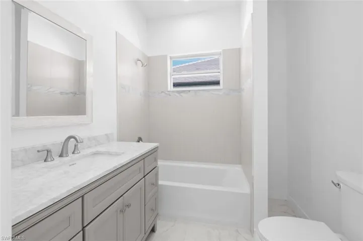 Full bathroom featuring tiled shower / bath combo, vanity, toilet, and tile floors