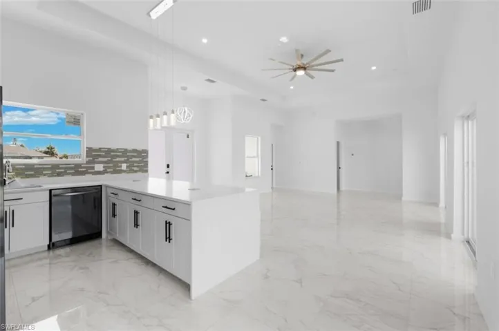 Kitchen with stainless steel dishwasher, kitchen peninsula, backsplash, ceiling fan, and light tile floors