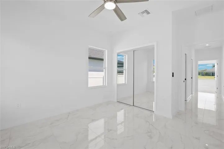 Unfurnished bedroom with a closet, light tile flooring, and ceiling fan