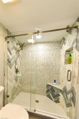 BEAUTIFULLY UPDATED OWNER'S SUITE WALK-IN SHOWER.  BARN-STYLE GLASS DOORS.  FULL-HEIGHT DESIGNER TILED WALLED.  SHOWER NICHE.  SHOWER SEAAT.