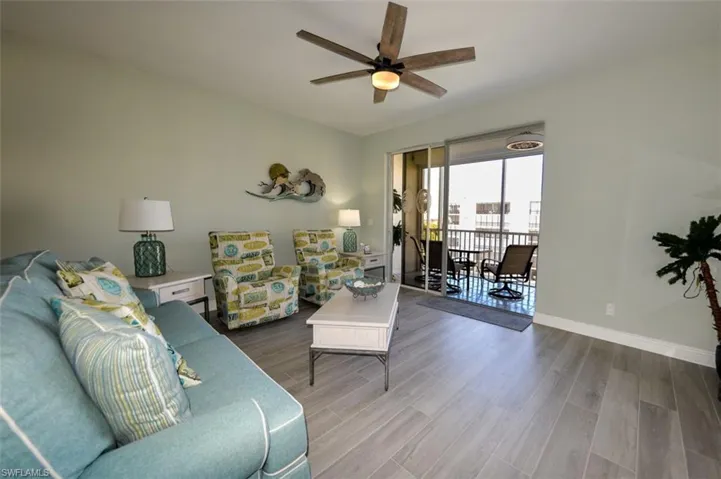 LIVING AREA SHOWING ENTRANCE TO LANAI.  WOOD-LOOK PLANK PORCELAIN TILE FLOORING THROUGHOUT.  UPDATED CEILING FAN W/LIGHT.  ENTRANCE TO OWNER'S SUITE IS TO RIGHT.