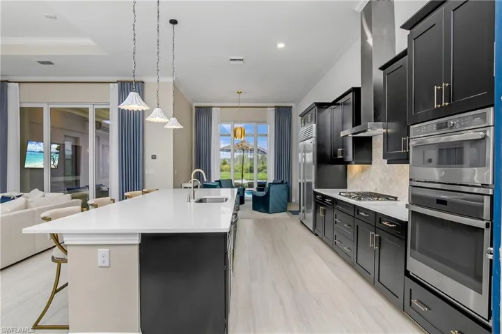 Kitchen featuring a kitchen bar, sink, appliances with stainless steel finishes, tasteful backsplash, and a center island with sink