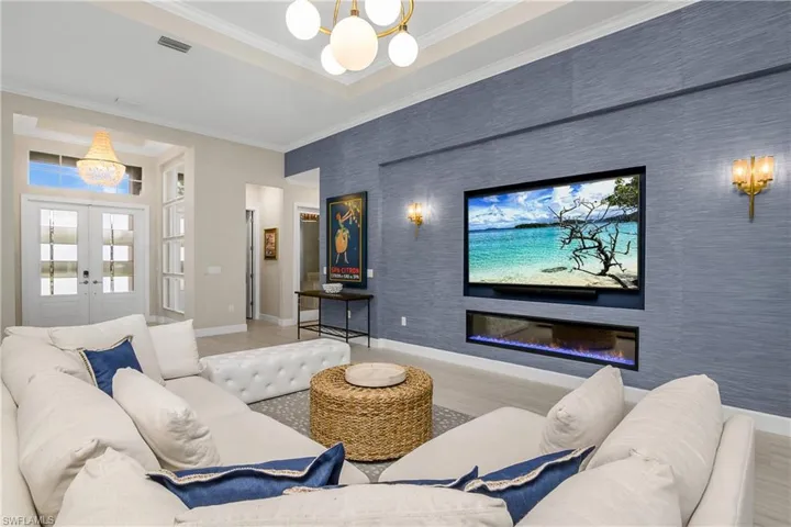 Home theater room with wood-type flooring, ornamental molding, and an inviting chandelier