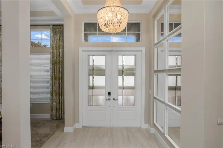 Entrance foyer featuring an inviting chandelier, french doors, and crown molding