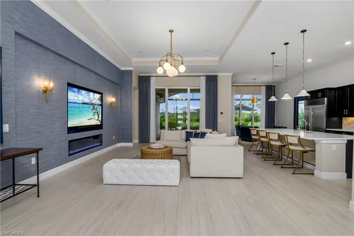 Tiled living room featuring sink, a notable chandelier, and a tray ceiling