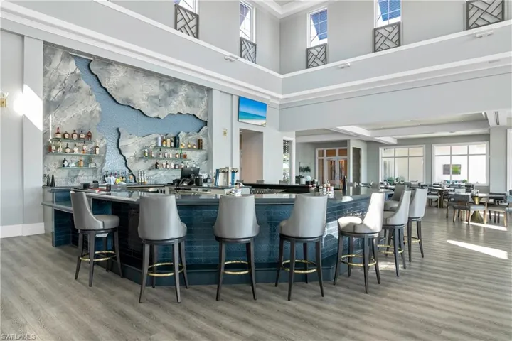 Bar featuring a towering ceiling and hardwood / wood-style flooring