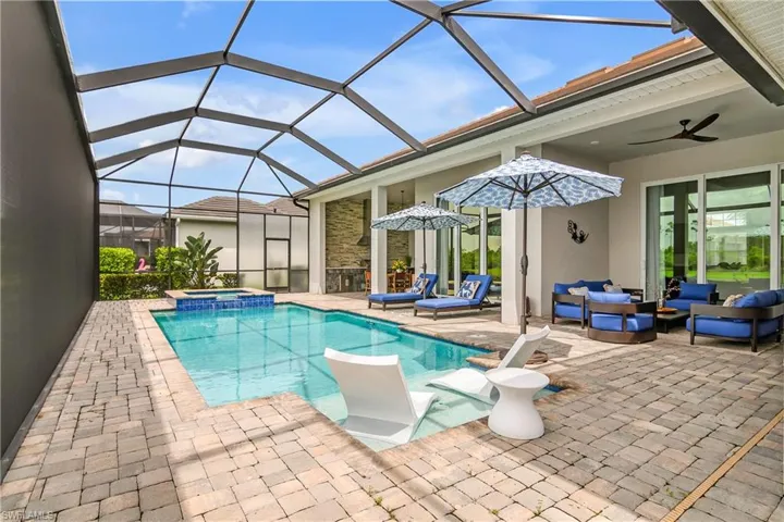 View of pool with glass enclosure, a patio area, an in ground hot tub, an outdoor hangout area, and ceiling fan