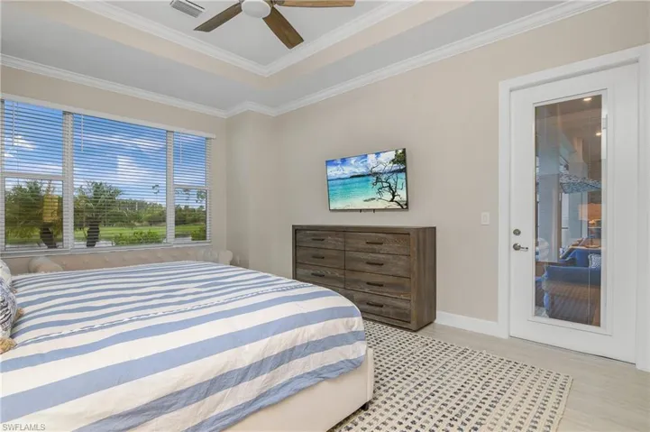 Bedroom with light hardwood / wood-style flooring, ceiling fan, a raised ceiling, and ornamental molding
