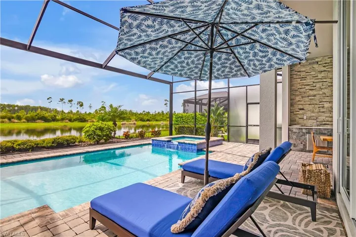 View of pool featuring an in ground hot tub, glass enclosure, a patio, and a water view