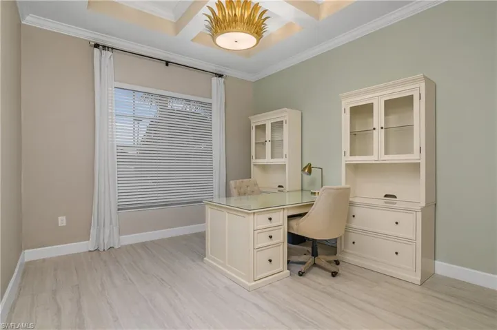 Office area with built in desk, light hardwood / wood-style floors, crown molding, and coffered ceiling