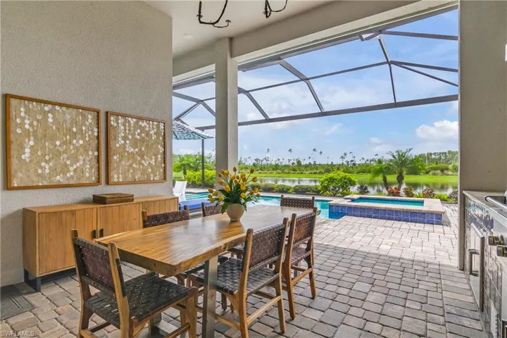 View of patio featuring glass enclosure, a water view, and a swimming pool with hot tub