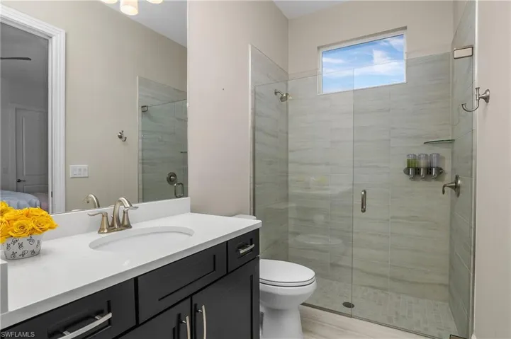 Bathroom featuring toilet, vanity, and walk in shower