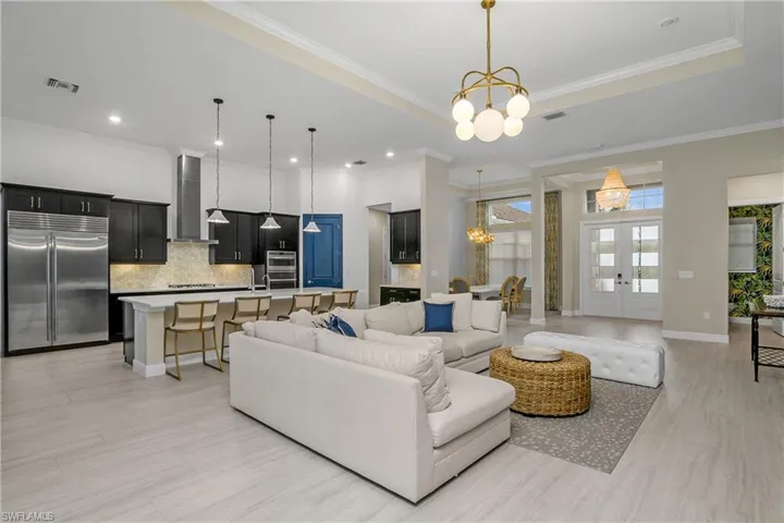 Living room featuring french doors, a tray ceiling, ornamental molding, and a chandelier