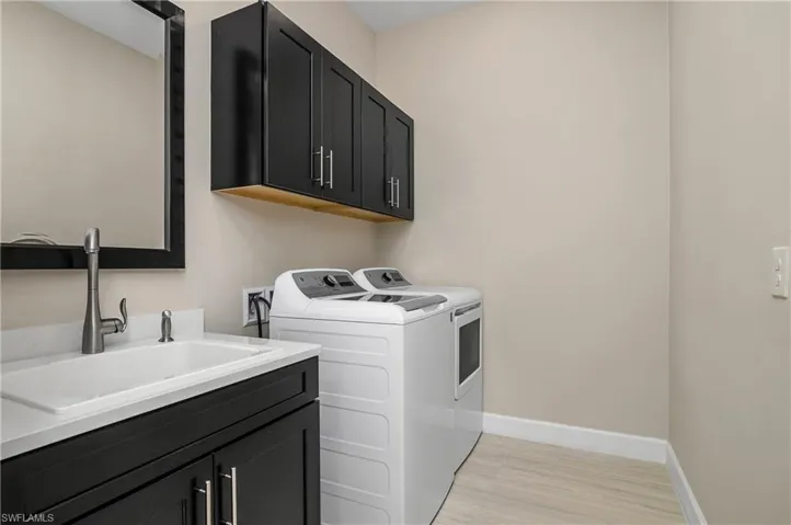 Washroom featuring washer and dryer, sink, light wood-type flooring, and cabinets