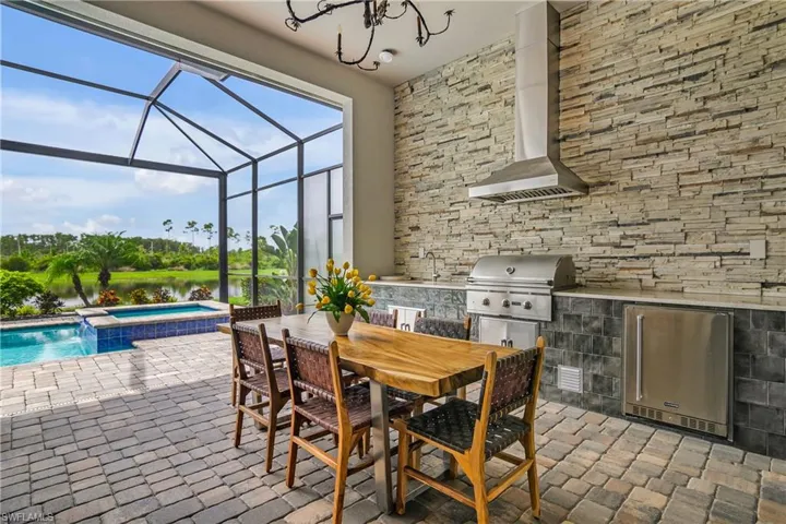 View of patio / terrace with glass enclosure, a pool with hot tub, sink, and area for grilling
