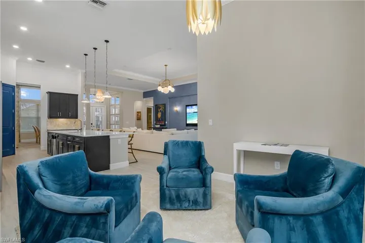 Living room featuring a wealth of natural light, a tray ceiling, a notable chandelier, and sink