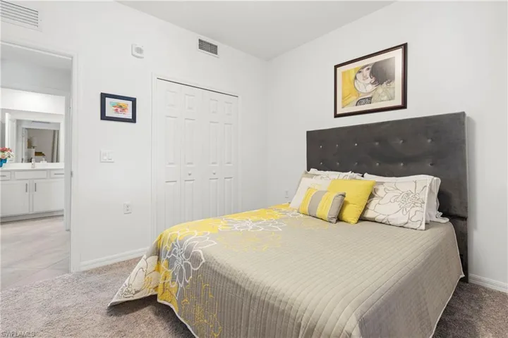 Bedroom with light colored carpet, a closet, and light tile patterned flooring