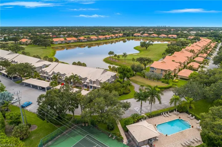 Aerial view of residential area featuring a golf club, a large body of water, and a pool area